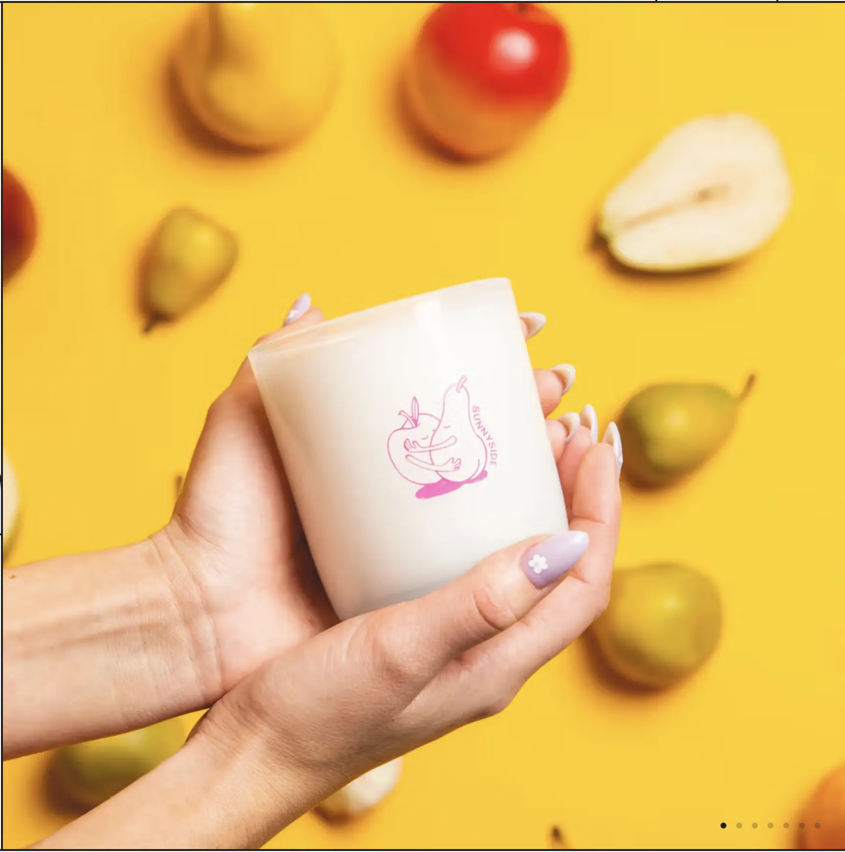 A Sunnyside candle held over a scatter of pears on yellow — one of the product lifestyle frames.