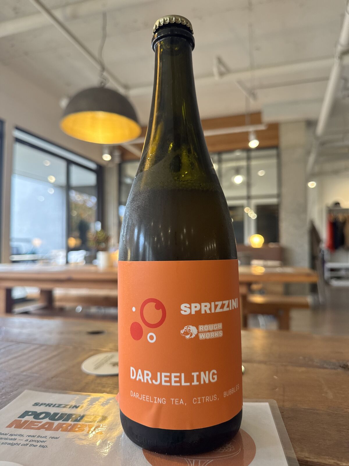 The Darjeeling bottle, terracotta label, standing on the Poured Nearby poster