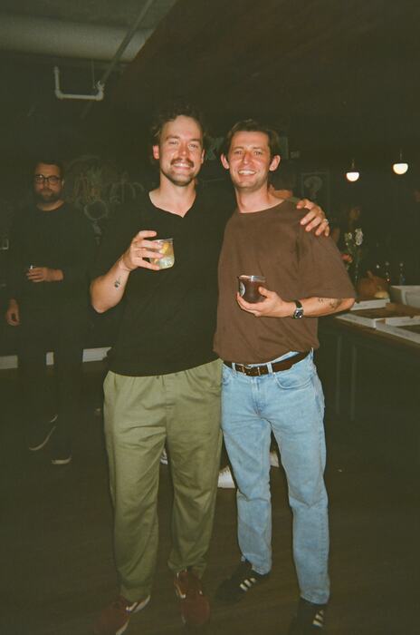 Two guests arm in arm by the staircase, drinks in hand