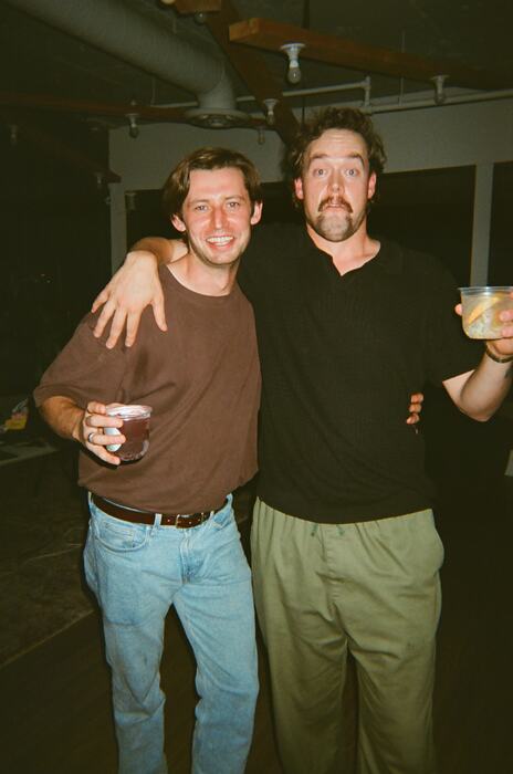 Two guests by the staircase, one holding a cup above his head
