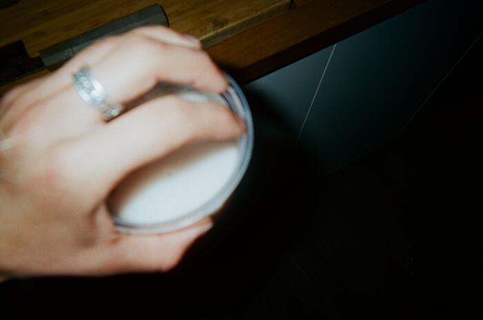 A hand with a silver ring resting over the top of a cup
