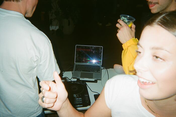 A guest laughing in the foreground with the DJ laptop behind