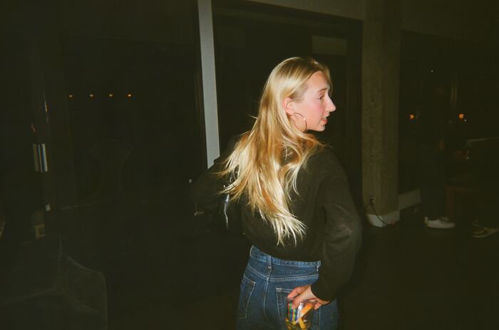 A guest with long blonde hair turning away, a drink held behind her back
