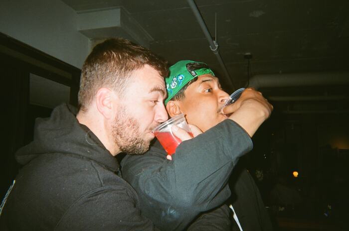 Two guests drinking with their arms linked