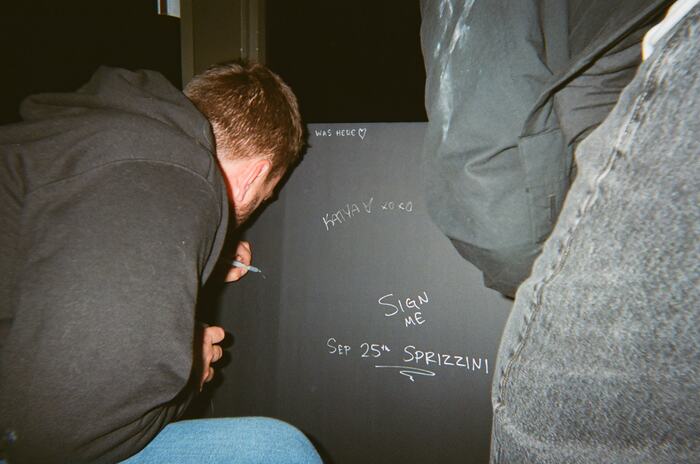 A guest writing on the black sign-me board