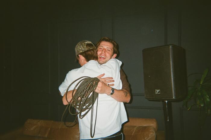 Two people hugging, one with a coil of cable over his shoulder