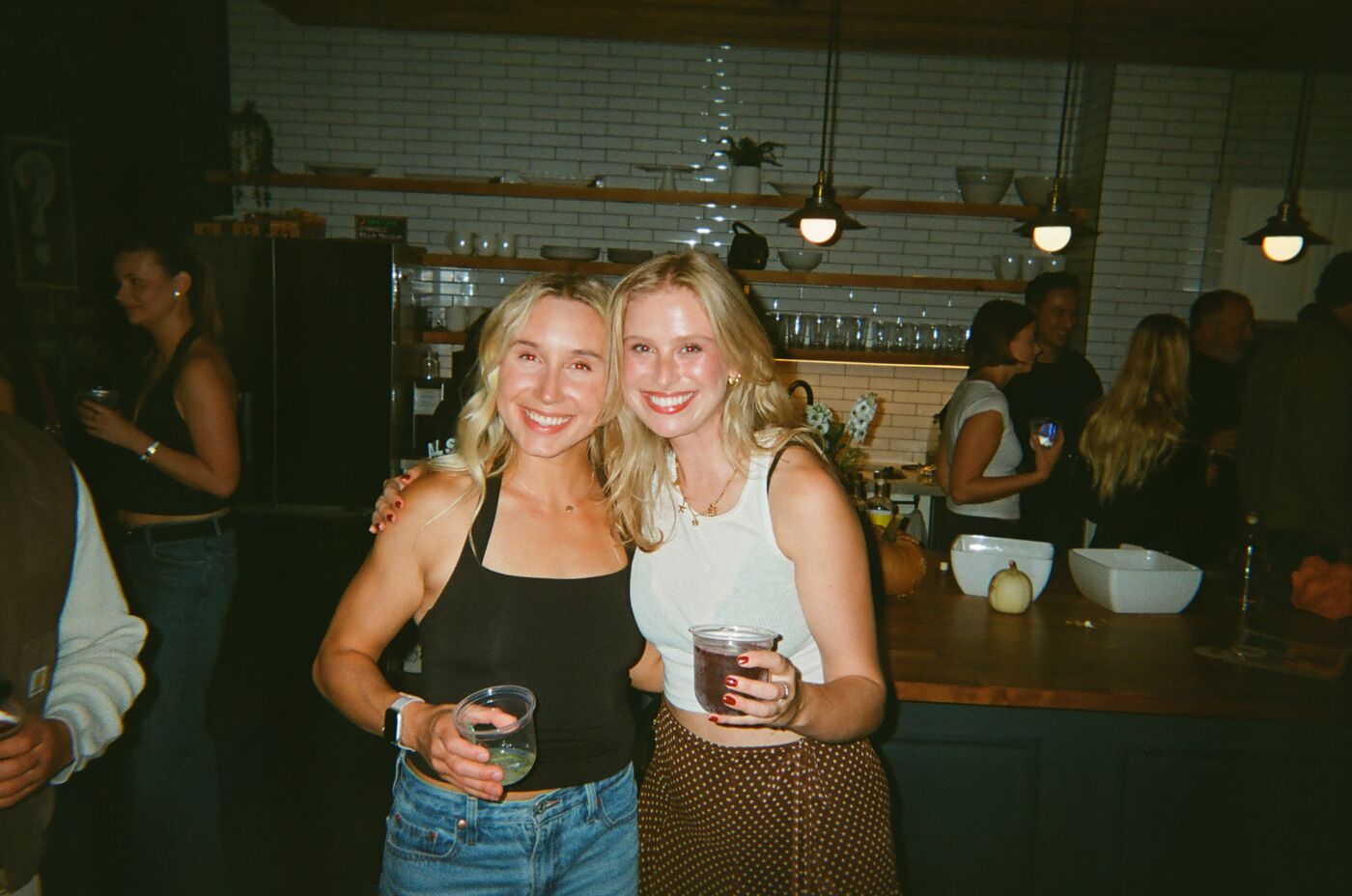 Two guests smiling with drinks in front of the kitchen island