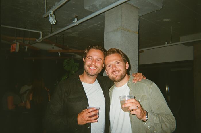 Two guests with an arm round each other, drinks raised