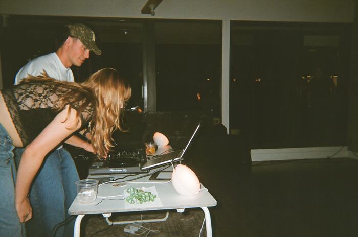 A guest and the DJ leaning over the decks