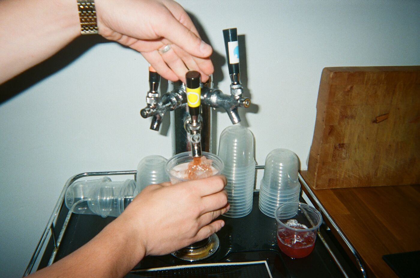 Two hands pouring a drink from the tap into a cup