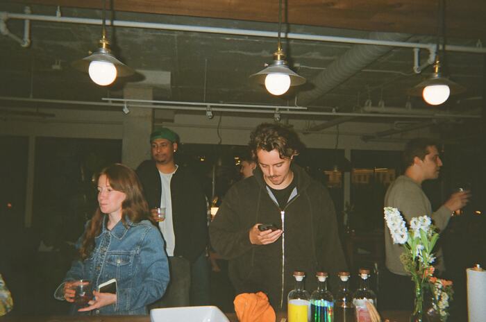 Guests at the counter behind a row of bottles and a jug of flowers