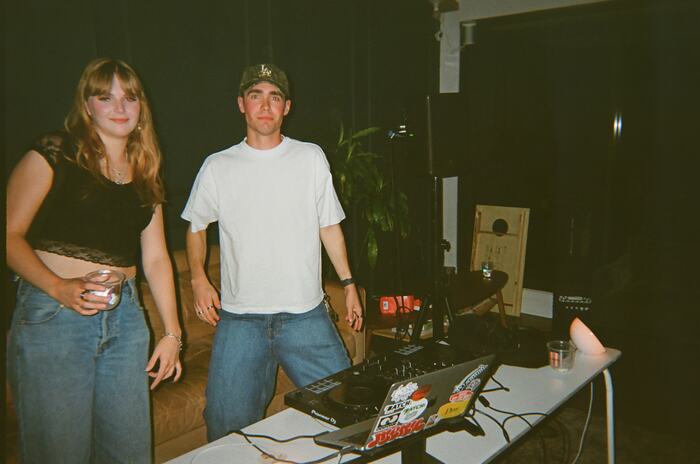 A guest and the DJ standing behind the decks