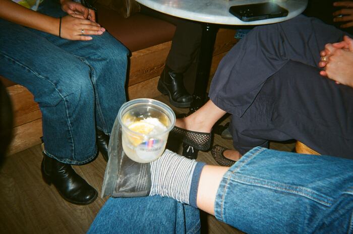 A cup balanced on a crossed ankle under the table