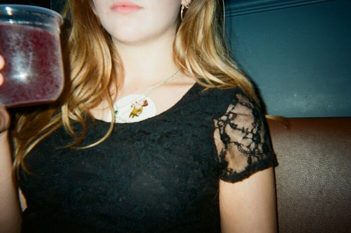 A guest in a black lace top holding up a dark red drink