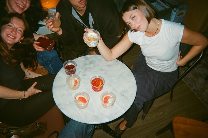 Guests round a small marble table covered in grapefruit-topped drinks
