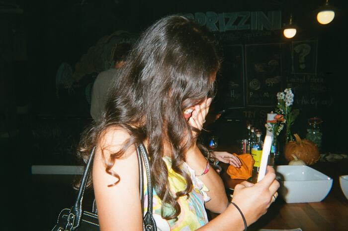 A guest with long dark hair looking at her phone by the counter