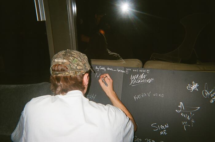 A guest in a camo cap signing the black board