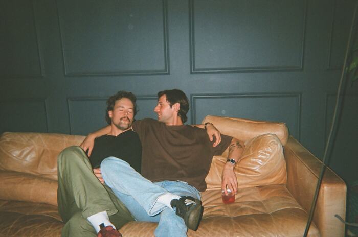 Two guests sprawled on the tan leather couch