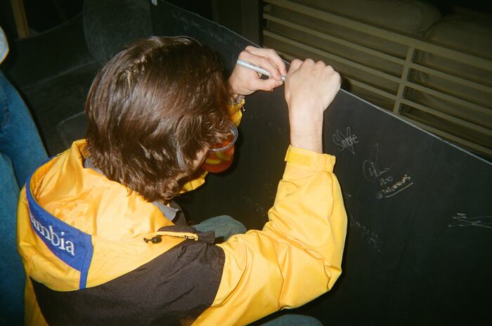 A guest in a yellow jacket signing the board