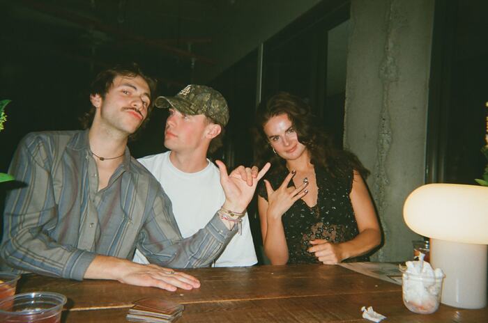 Three guests at the long table throwing hand signs