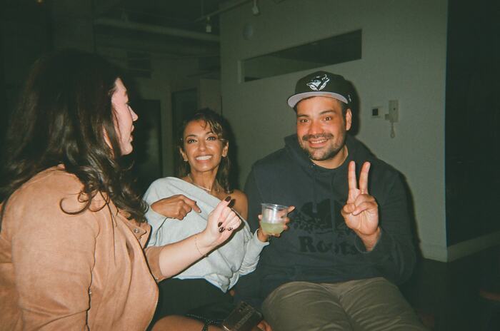 Three guests on the banquette, one holding a drink and a peace sign