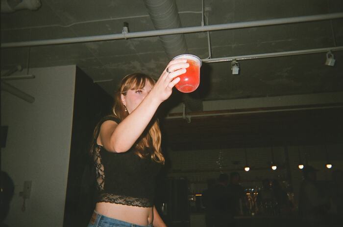 A guest holding a red drink above her head